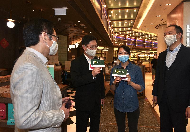 The Secretary for Innovation and Technology, Mr Alfred Sit (second left), chats with an operator of a local cafe kitchen during his visit to Tsuen Wan today (November 21) to learn more about the implementation of the "LeaveHomeSafe" mobile app. Looking on are Managing Director of the Urban Renewal Authority, Ir Wai Chi-sing (first left); and the Deputy Chairman of the Sino Group, Mr Daryl Ng (first right).