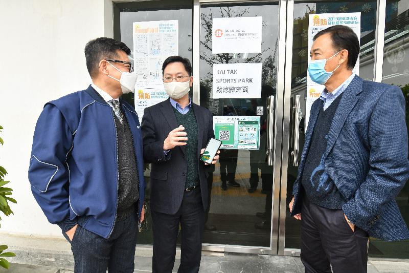 The Secretary for Innovation and Technology, Mr Alfred Sit (centre), today (December 17) sees for himself the implementation of the "LeaveHomeSafe" mobile app at the Kai Tak Sports Park construction site. Looking on are the Executive Director of the Construction Industry Council, Mr Albert Cheng (left), and the Managing Director of Hip Hing Construction, Mr Chu Tat-chi (right).