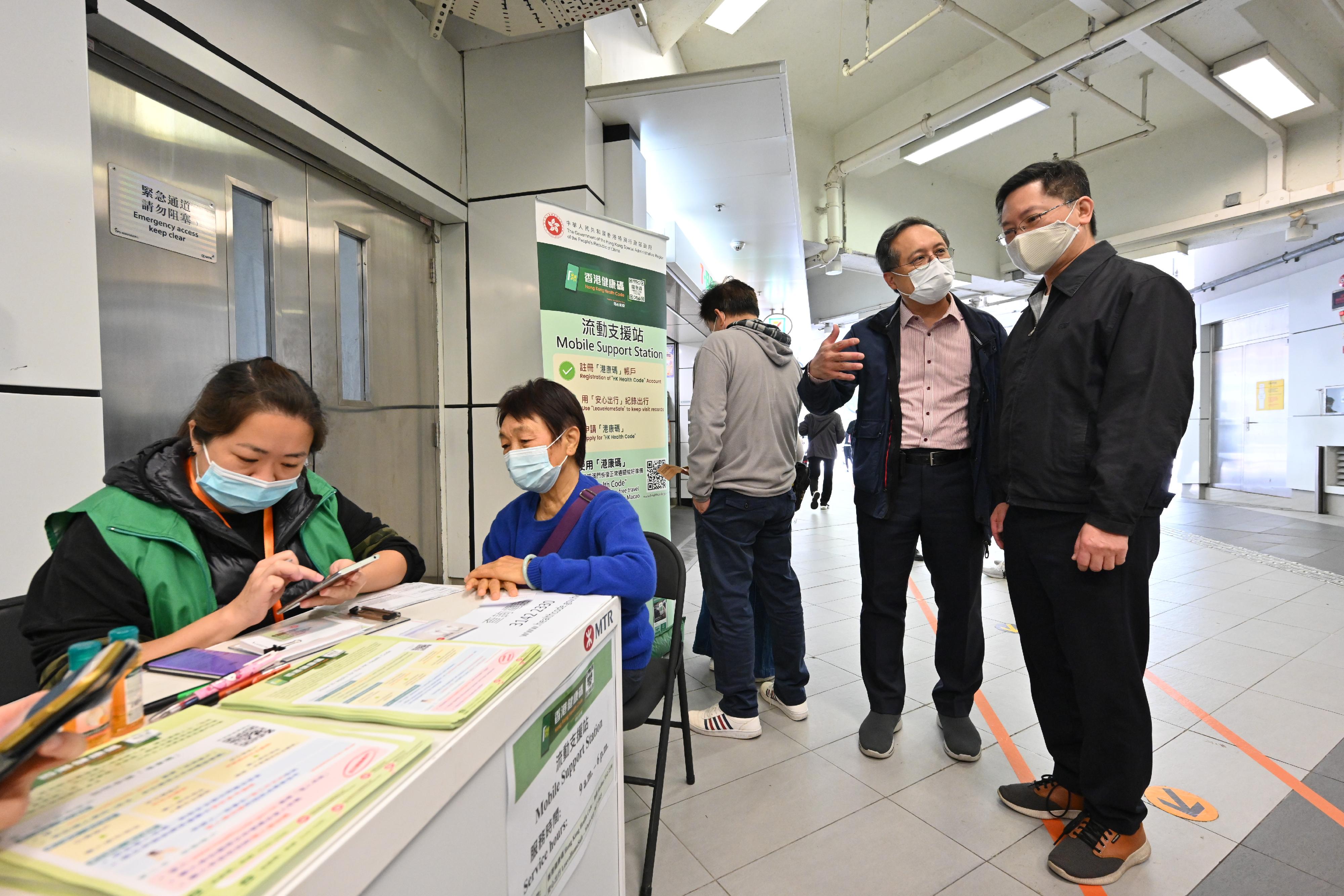 創新及科技局局長薛永恒（右一）今日（十二月二十五日）視察設於大埔墟港鐵站的「香港健康碼」（「港康碼」）流動支援站，聽取助理政府資訊科技總監（產業發展）黃敬文（右二）講述外展隊如何協助有需要的市民辦理申請「港康碼」相關手續。