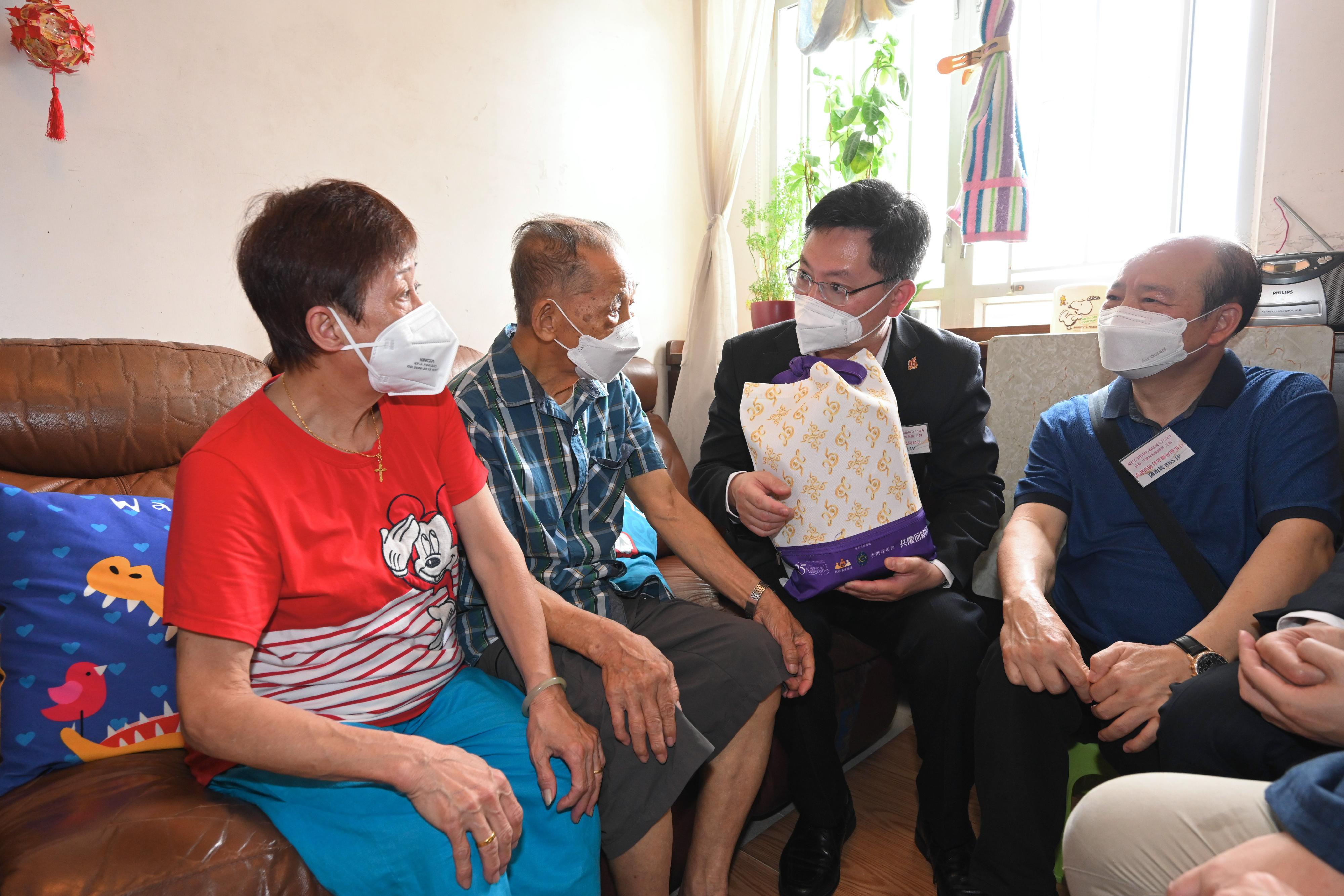 創新及科技局局長薛永恒（右二）今日（六月十六日）探望石排灣邨一戶雙老家庭，並向他們送上香港特別行政區成立二十五周年慶祝活動禮物包，以關懷行動共慶回歸。旁為香港南區各界聯會理事長陳南坡（右一）。